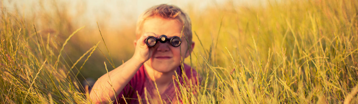 Junge mit Fernglas im Gras
