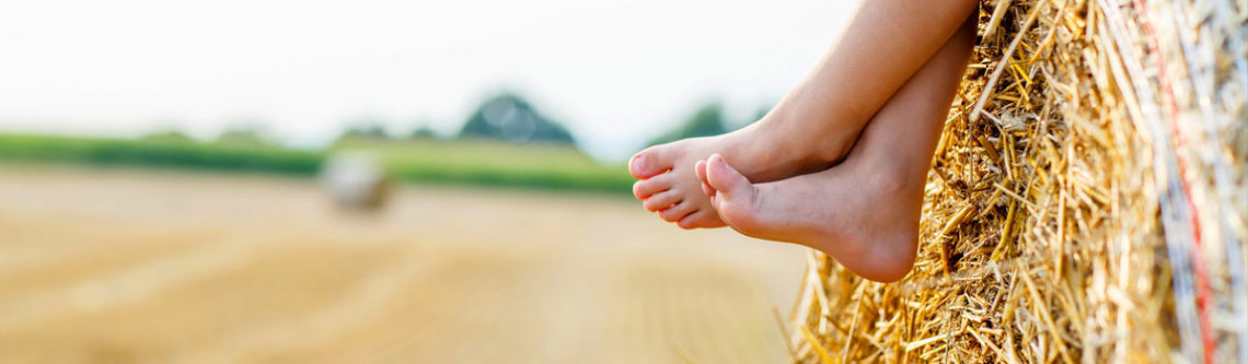 Kinderfüße auf einem Strohballen